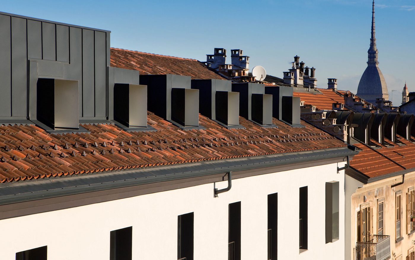 Copertura riqualificata dell’immobile RIV. 6 con tetto in coppi, nuovi abbaini metallici e volumi superiori integrati; sullo sfondo si distingue la Mole Antonelliana.