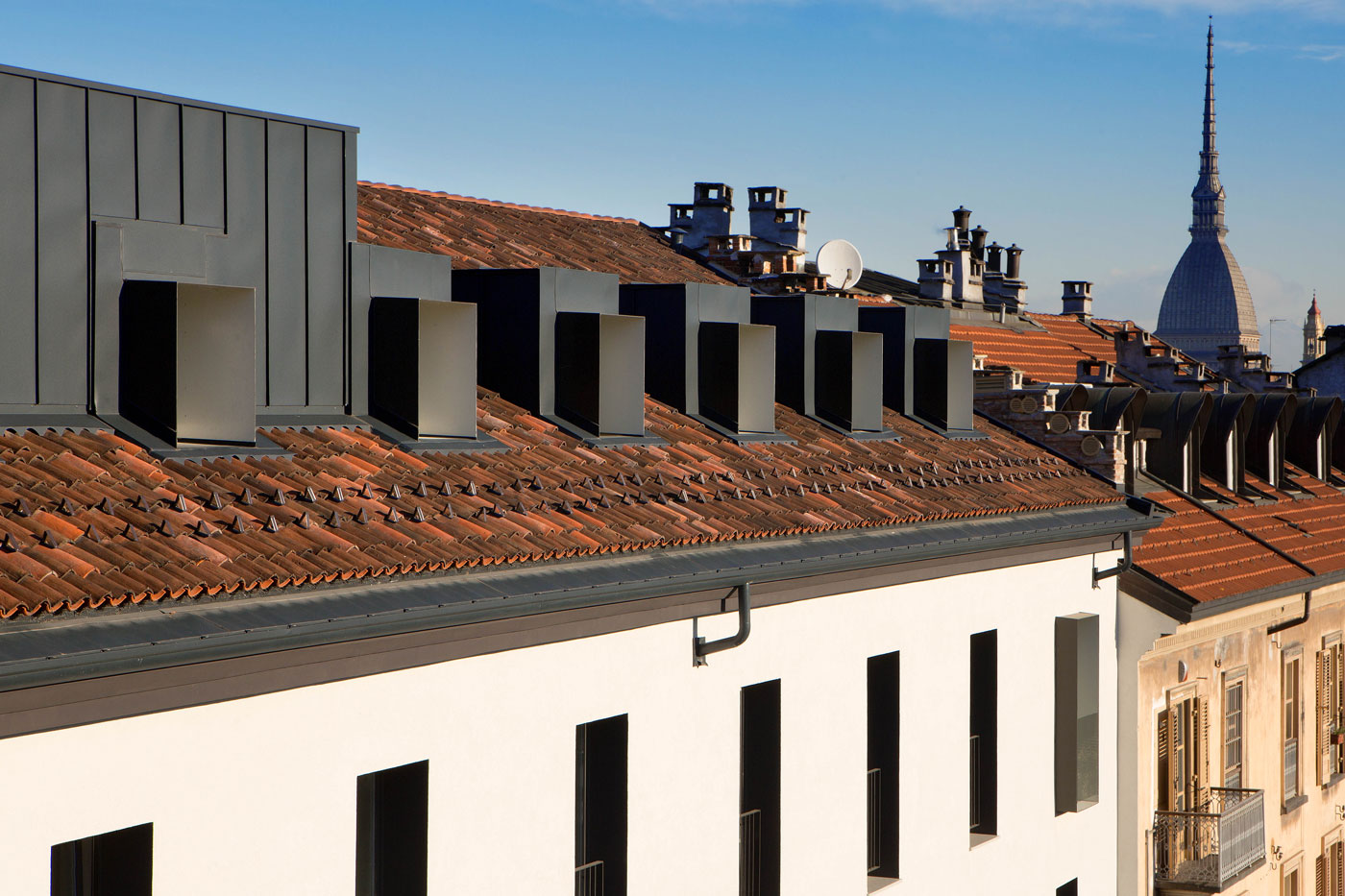 Copertura riqualificata dell’immobile RIV. 6 con tetto in coppi, nuovi abbaini metallici e volumi superiori integrati; sullo sfondo si distingue la Mole Antonelliana.