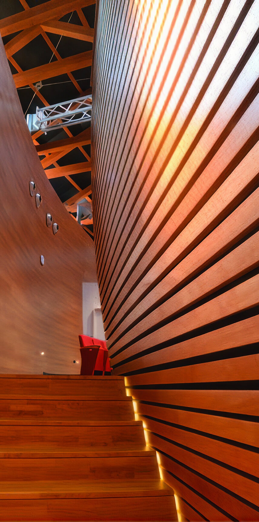 Interno moderno con scala in legno, pareti curate con listelli in legno illuminati da strisce LED e travi a vista sul soffitto.
